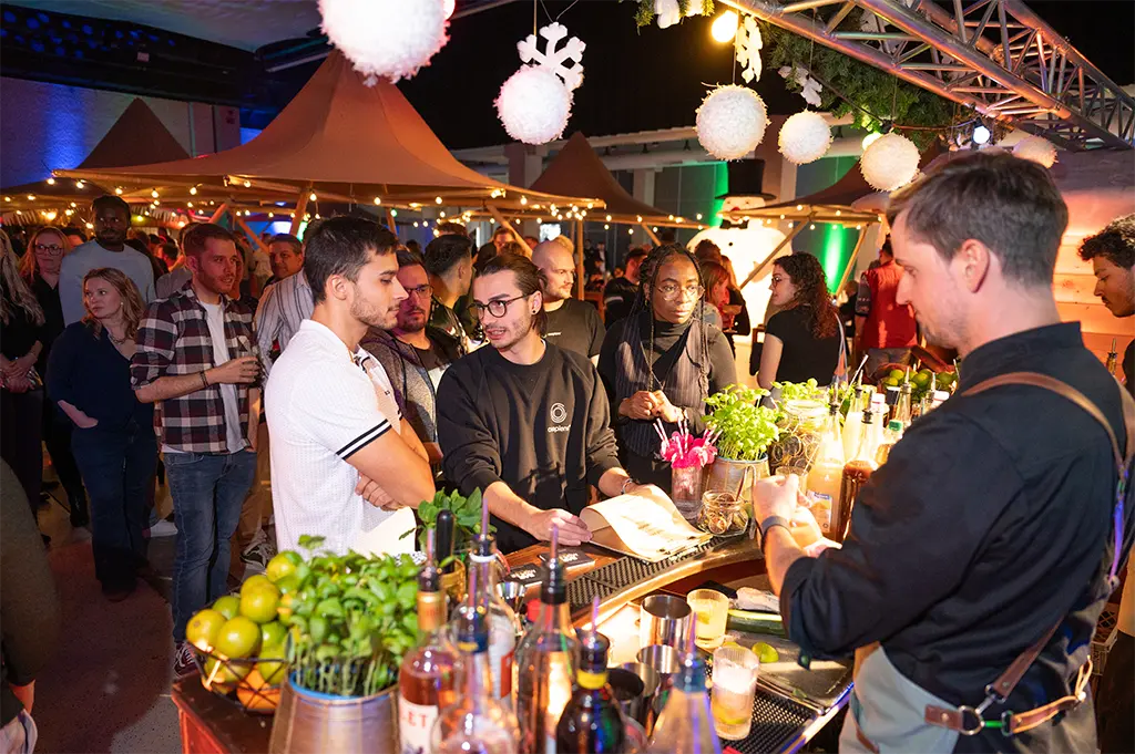 Gäste an der Bar beim Skandinavische-Weihnachten-Event in Indoor-Tipidorf in Mannheim – festliche Firmenfeier mit nordischem Flair, Winterdeko und stimmungsvoller Eventhütten-Atmosphäre