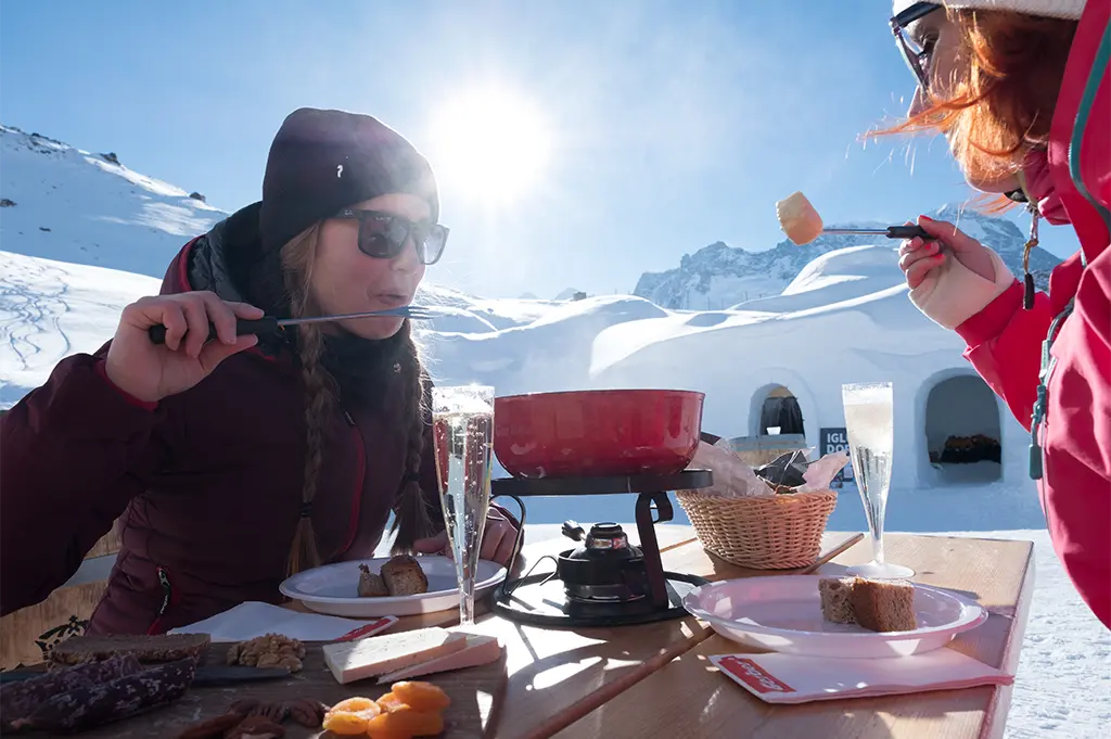 Teilnehmerinnen genießen Outdoor-Fondue mit Champagner vor einem Igludorf in Zermatt – exklusives Winter-Incentive mit Alpenblick, Kulinarik und Teamerlebnis im Schnee