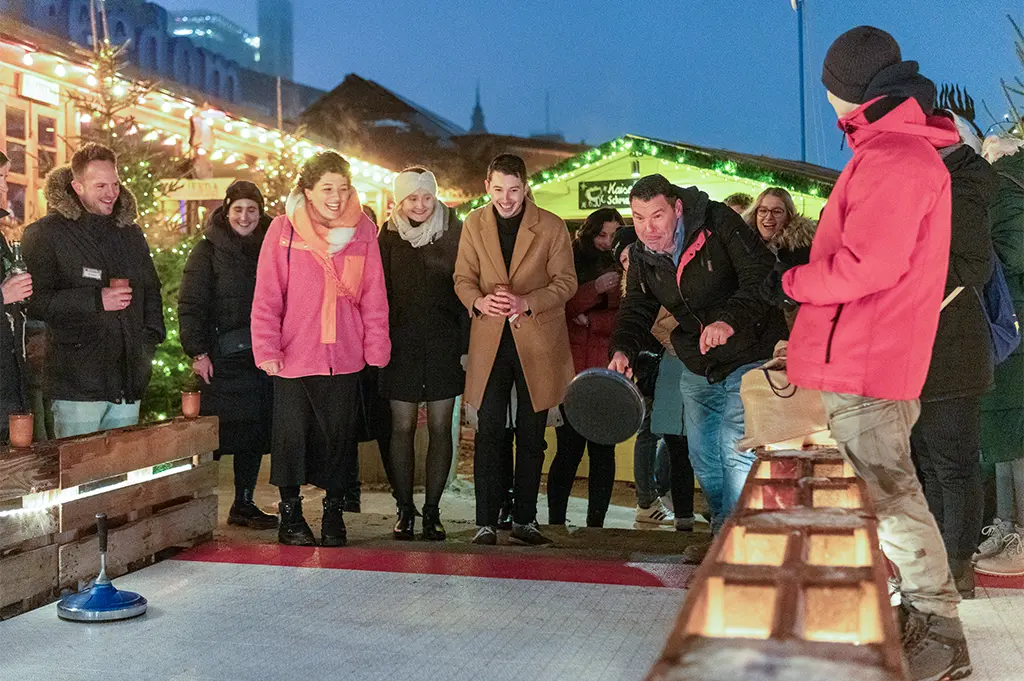 Firmenfeier mit Eisstockschießen beim mobilen Weihnachtsmarkt in München – stimmungsvolles Winterevent mit Lichterdeko, Teamspaß und Après-Ski-Flair