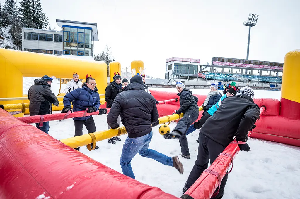 Team spielt Menschenkicker im Schnee beim Winter-Teamevent in Oberstdorf – actiongeladener Riesentischkicker für Teamspaß, Bewegung und Wintergaudi