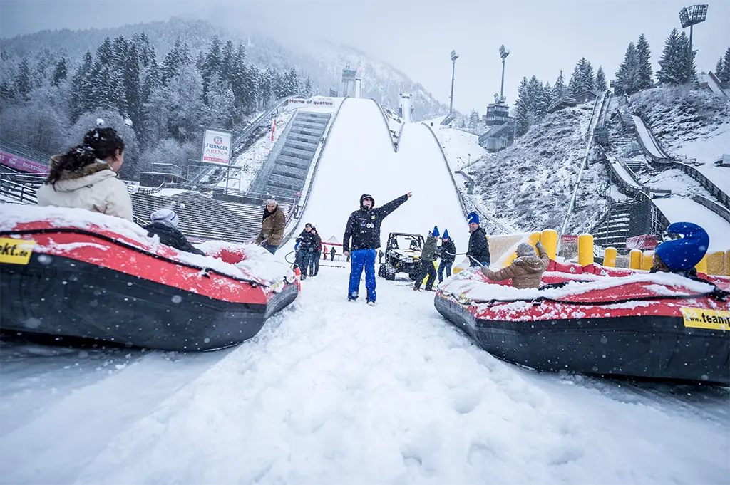 Team zieht Snowraft-Boot zur Rampe beim Winter-Incentive in Sonthofen  – rasantes Teamevent mit Action, Adrenalin und Schneespaß in den Alpen