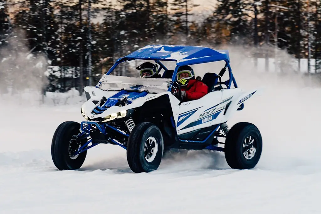 Zwei Teilnehmer driften mit einem Side-by-Side-Buggy über Schnee beim Winter-Fahrevent in Schwedisch-Lappland – rasanter Fahrspaß, Teambuilding und Adrenalin im hohen Norden
