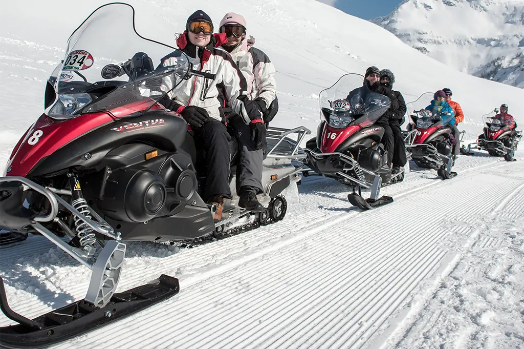 Teilnehmergruppe auf Schneemobilen bei geführter Wintertour in der Madesimo – actionreiche Schneesafari mit Panoramablick, Teambuilding und Fahrspaß in Italien und den Tiroler Alpen