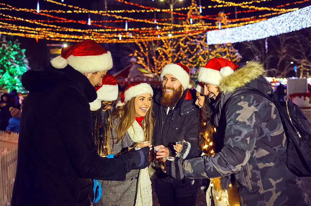 Kollegen mit Nikolausmützen stoßen beim Weihnachtsmarkt-Teamevent in Colmar an – festliche Winterrallye mit Lichterglanz, Glühwein und Teamspaß in der Altstadt