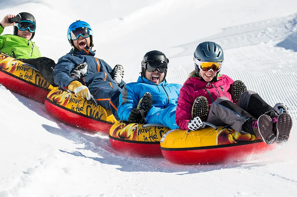 Vierköpfiges Team beim Snowtubing-Teamevent in Saalbach-Hinterglemm – rasanter Winterspaß auf Schnee mit Action, Teamgefühl und Alpenpanorama